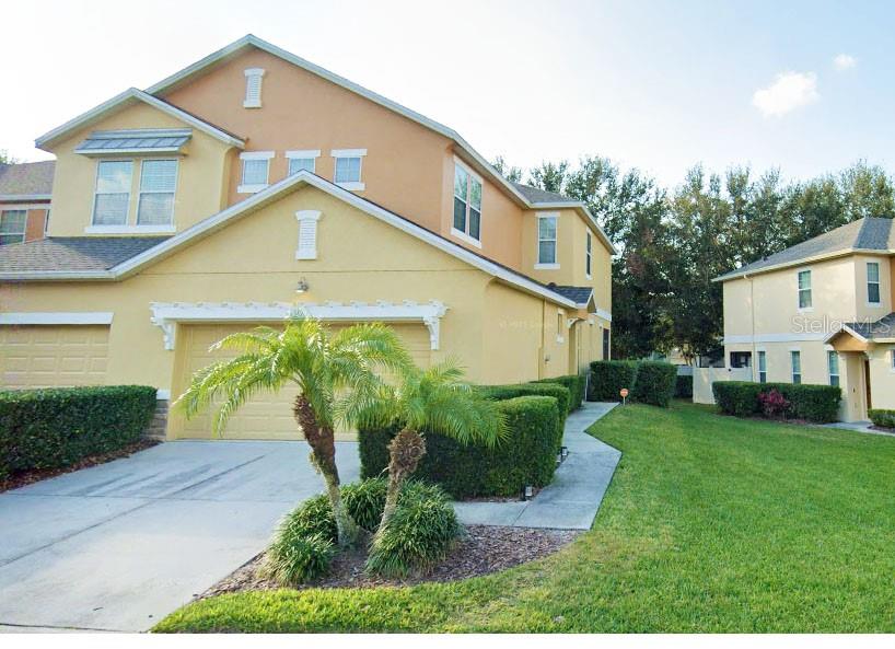 A two-story yellow townhouse with a palm tree in the front yard — 1338 GLENLEIGH DRIVE, OCOEE, FL