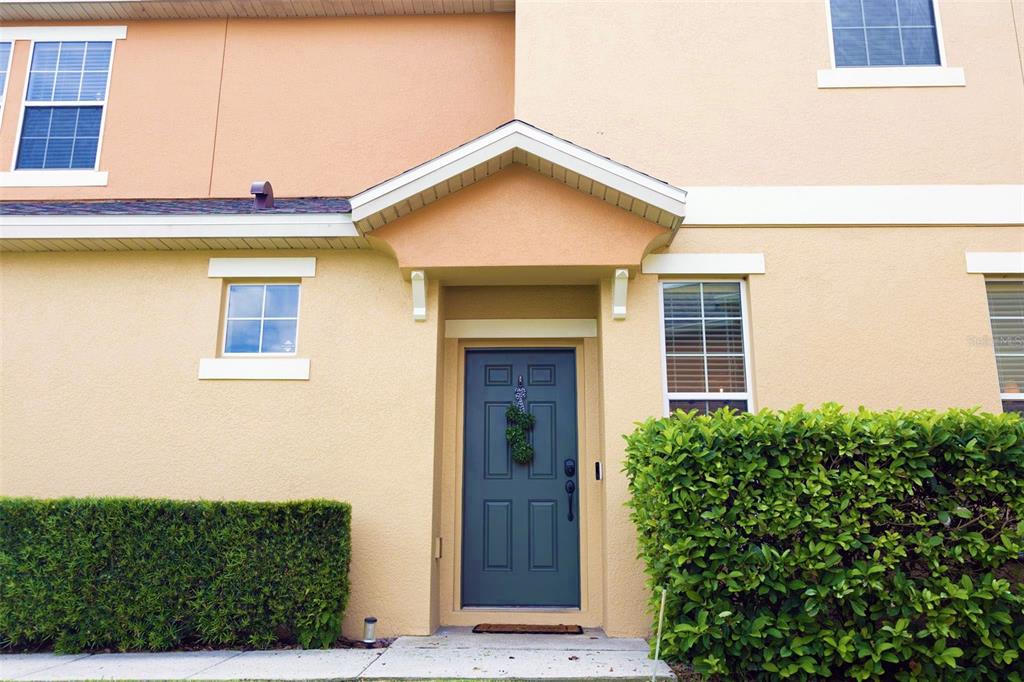 The exterior of a two-story townhouse features a blue front door and manicured hedges — 1338 GLENLEIGH DRIVE, OCOEE, FL