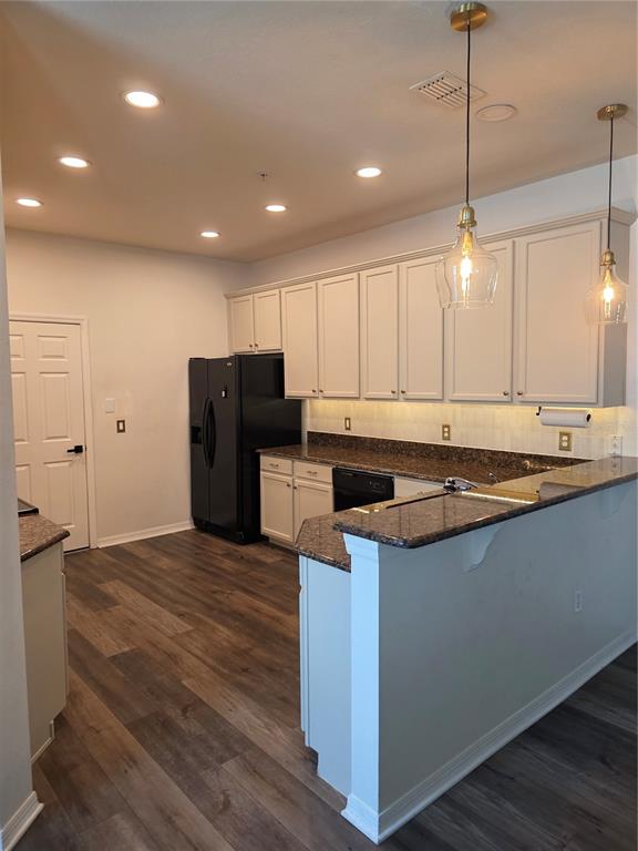 A kitchen features light-colored cabinets, dark granite countertops, black appliances, and wood-look flooring — 1338 GLENLEIGH DRIVE, OCOEE, FL