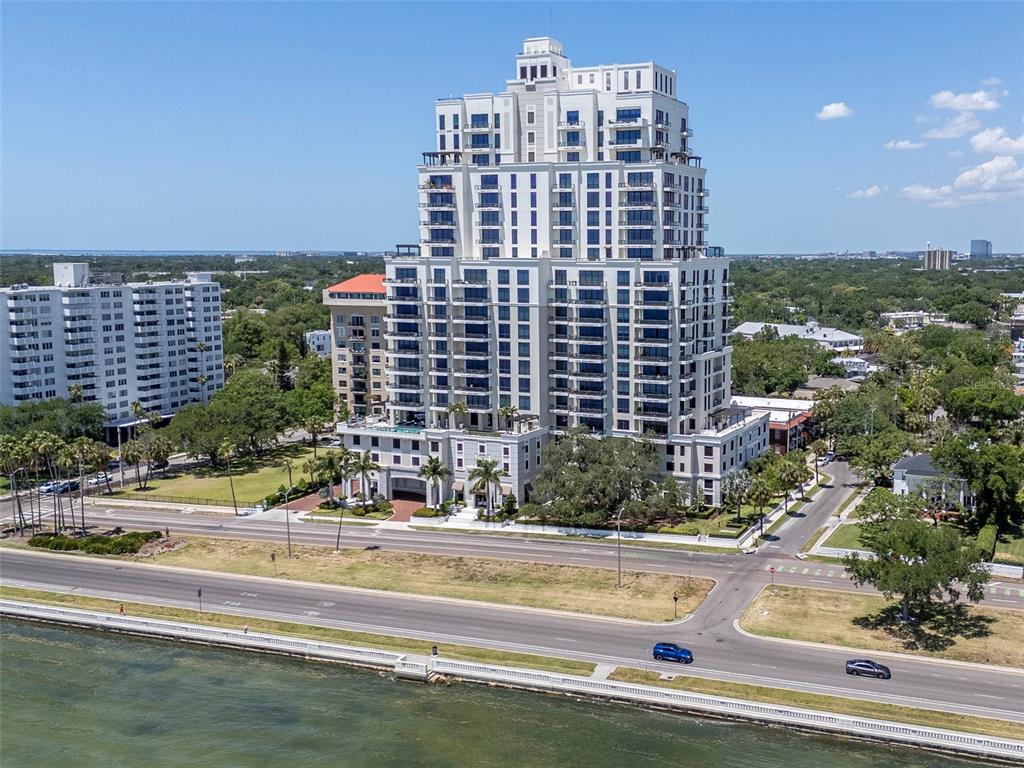 An aerial view shows a tall, multi-story residential building situated near a waterfront road — 2103 BAYSHORE BOULEVARD UNIT 602, TAMPA, FL