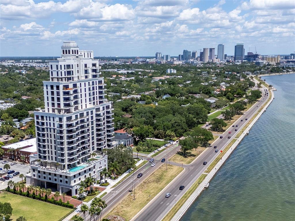 An aerial view shows a tall residential building next to a coastal road and water — 2103 BAYSHORE BOULEVARD UNIT 602, TAMPA, FL