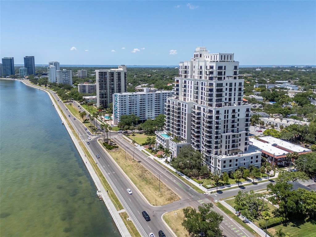 An aerial view shows a tall residential building beside a coastal road and water — 2103 BAYSHORE BOULEVARD UNIT 602, TAMPA, FL