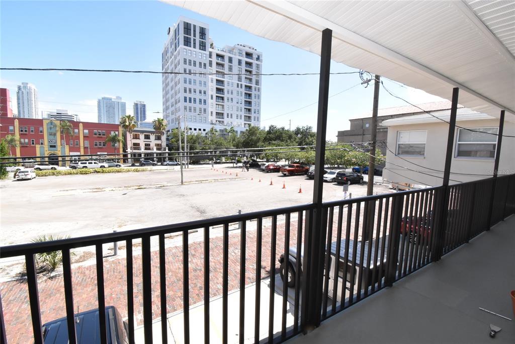 A balcony with a black railing overlooks a parking lot and city buildings — 220 6TH AVENUE N UNIT 11, ST PETERSBURG, FL