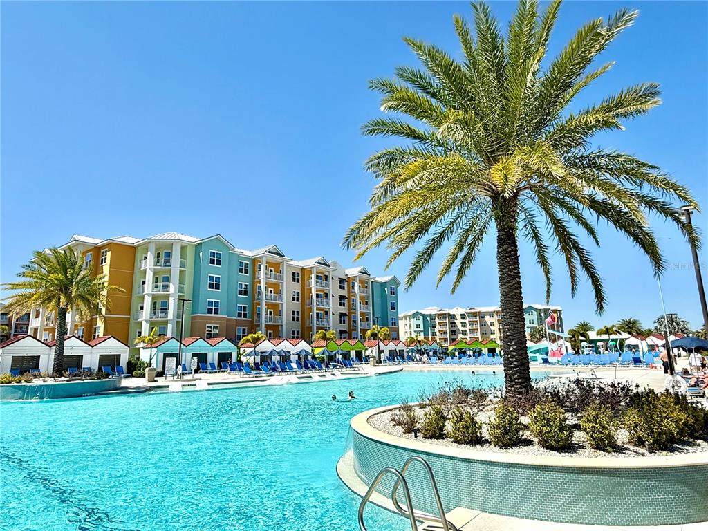 A large swimming pool with a palm tree island sits in front of multi-story buildings — 3151 SUNSET WALK DRIVE UNIT 208, KISSIMMEE, FL