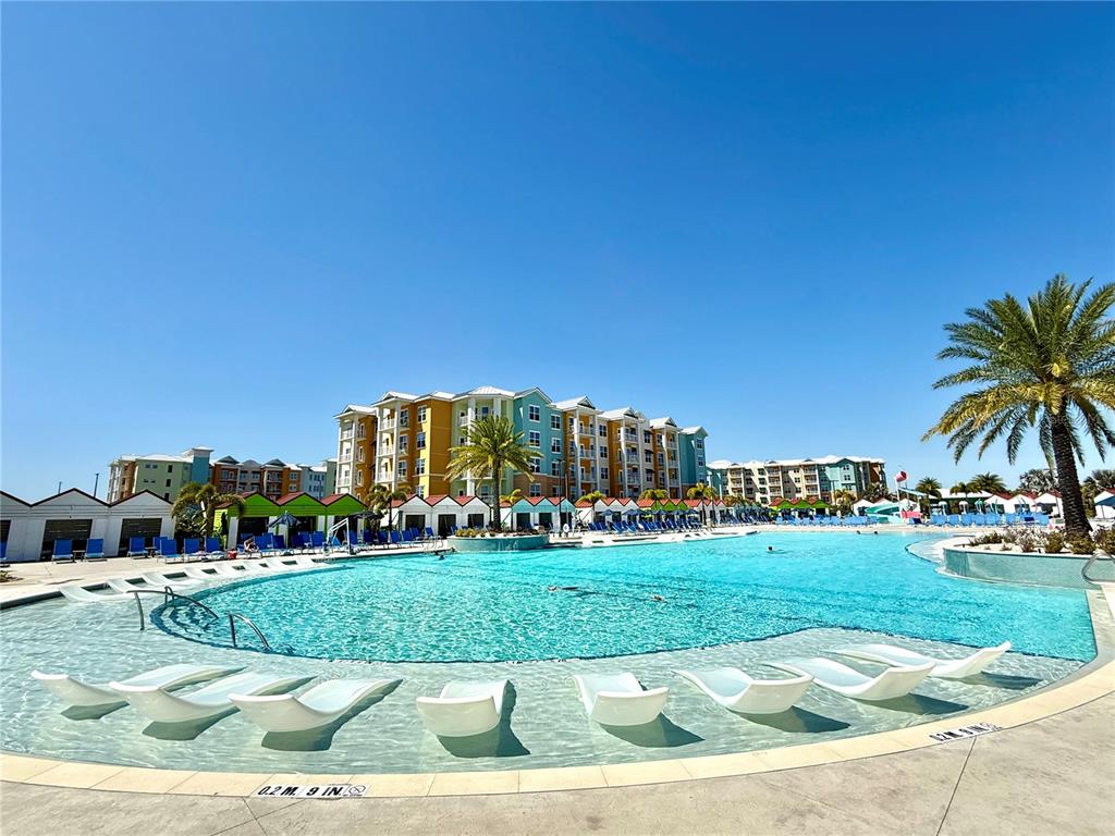 A large swimming pool with lounge chairs sits in front of a multi-story resort building — 3151 SUNSET WALK DRIVE UNIT 208, KISSIMMEE, FL