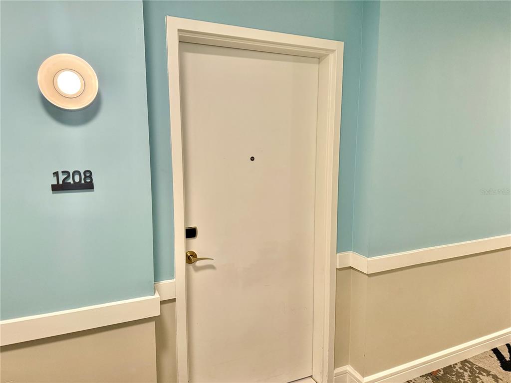 A white door with a peephole and electronic lock is set in a light blue wall — 3151 SUNSET WALK DRIVE UNIT 208, KISSIMMEE, FL