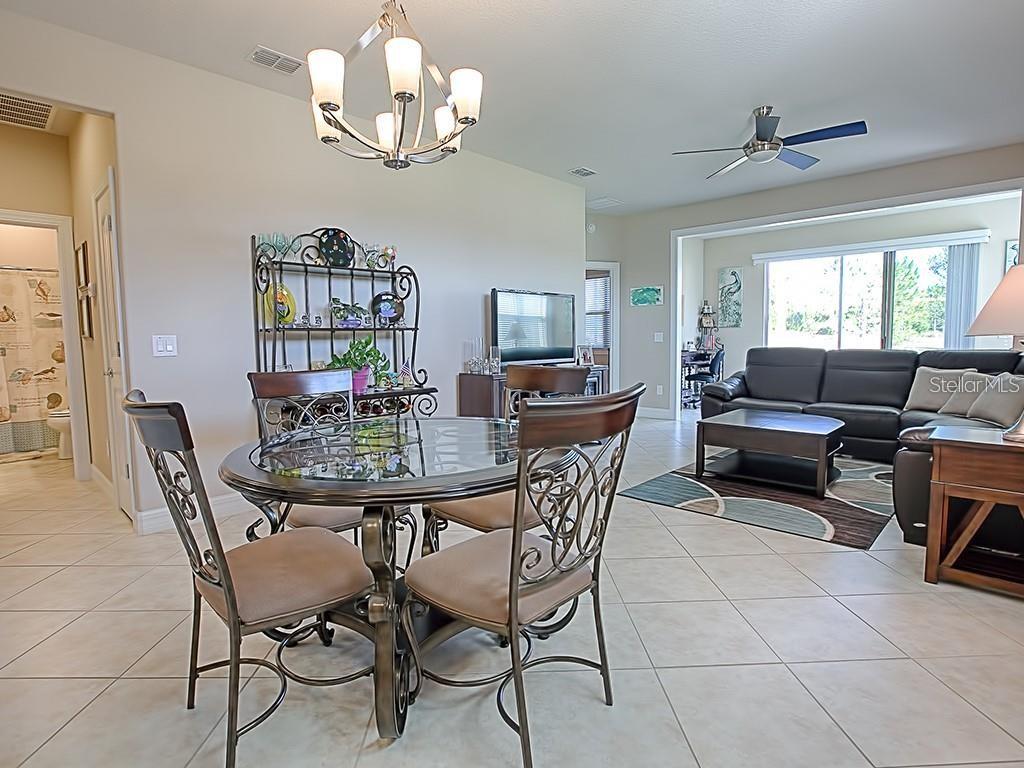 A dining area with a glass-topped table and metal chairs opens into a living room — 7732 SW 94TH CIRCLE, OCALA, FL
