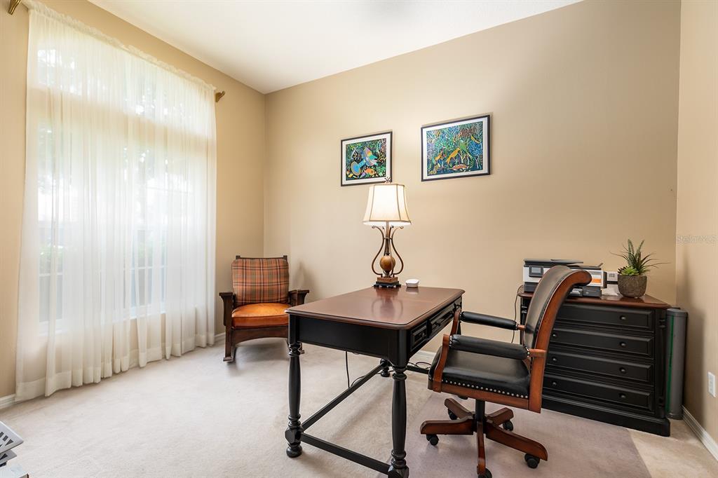 A home office features a dark wood desk, a leather chair, and a window with curtains — 6631 CRESTMONT GLEN LANE, WINDERMERE, FL