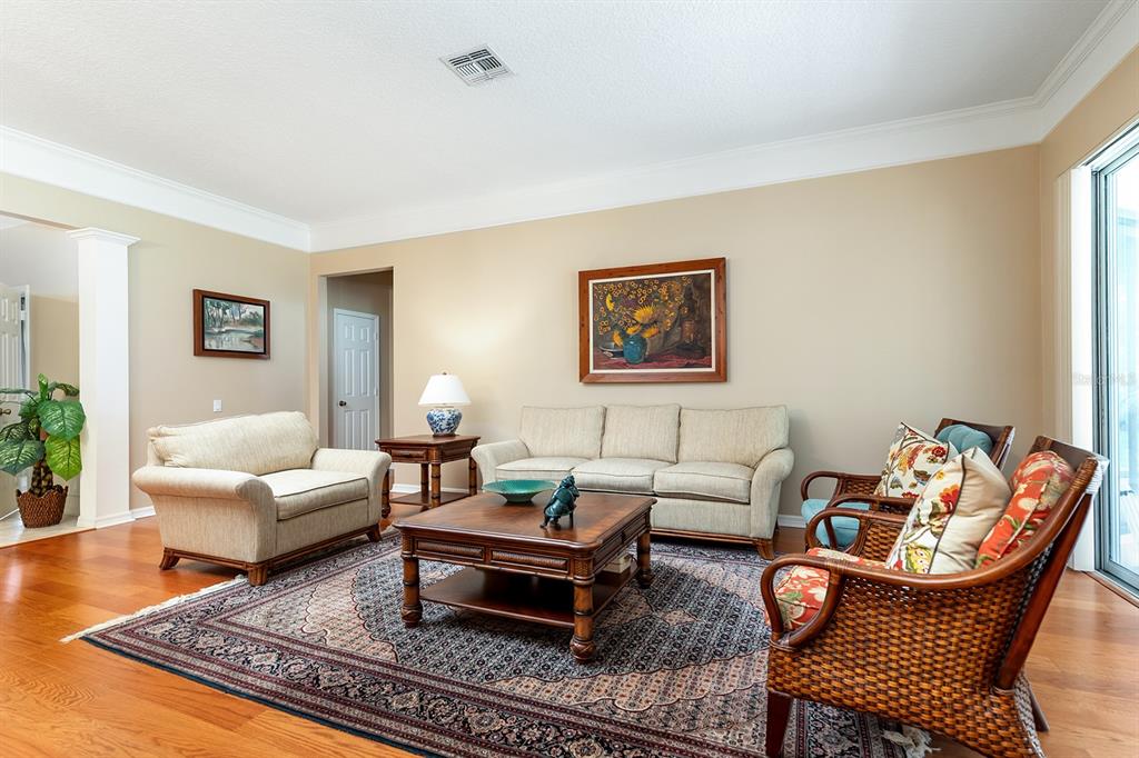 A living room features a beige sofa, matching loveseat, wicker chairs, and a patterned area rug — 6631 CRESTMONT GLEN LANE, WINDERMERE, FL