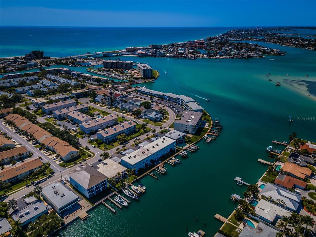 An aerial view shows a coastal residential area with multi-story buildings, boat docks, and waterways — 12305 3RD STREET E UNIT 2, TREASURE ISLAND, FL