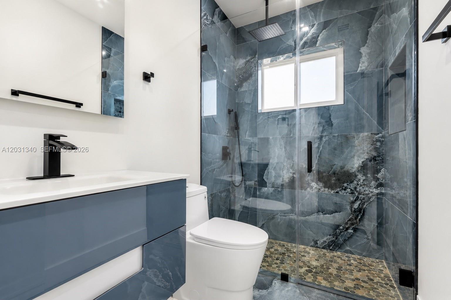 A modern bathroom features a blue marble-tiled walk-in shower, a floating vanity, and black fixtures — 8819 Dickens Ave, Surfside FL 33154, SURFSIDE, FL