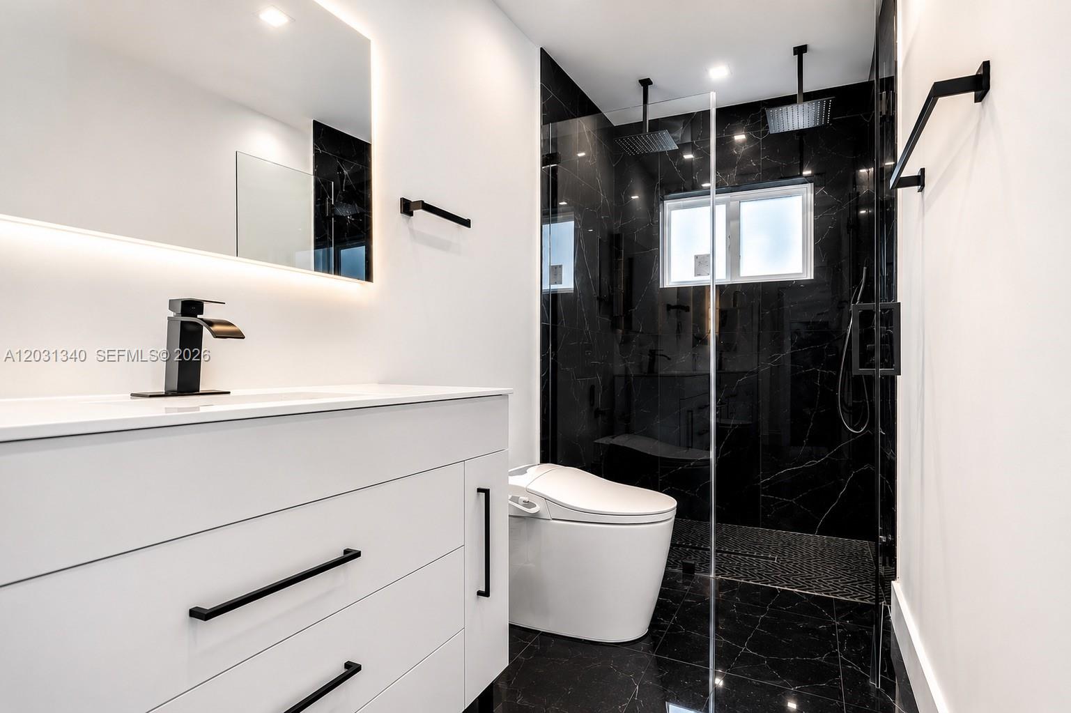 A modern bathroom features a white vanity, black fixtures, and a glass-enclosed black marble shower — 8819 Dickens Ave, Surfside FL 33154, SURFSIDE, FL