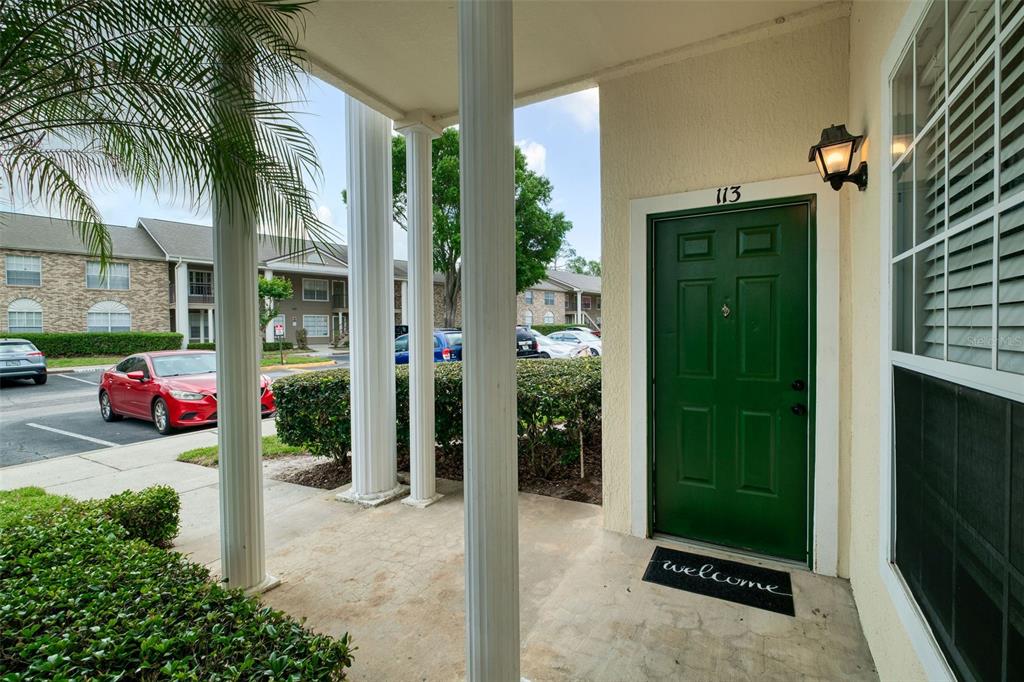 A green front door with the number 113 sits under a covered porch with columns — 141 RESERVE CIRCLE UNIT 113, OVIEDO, FL
