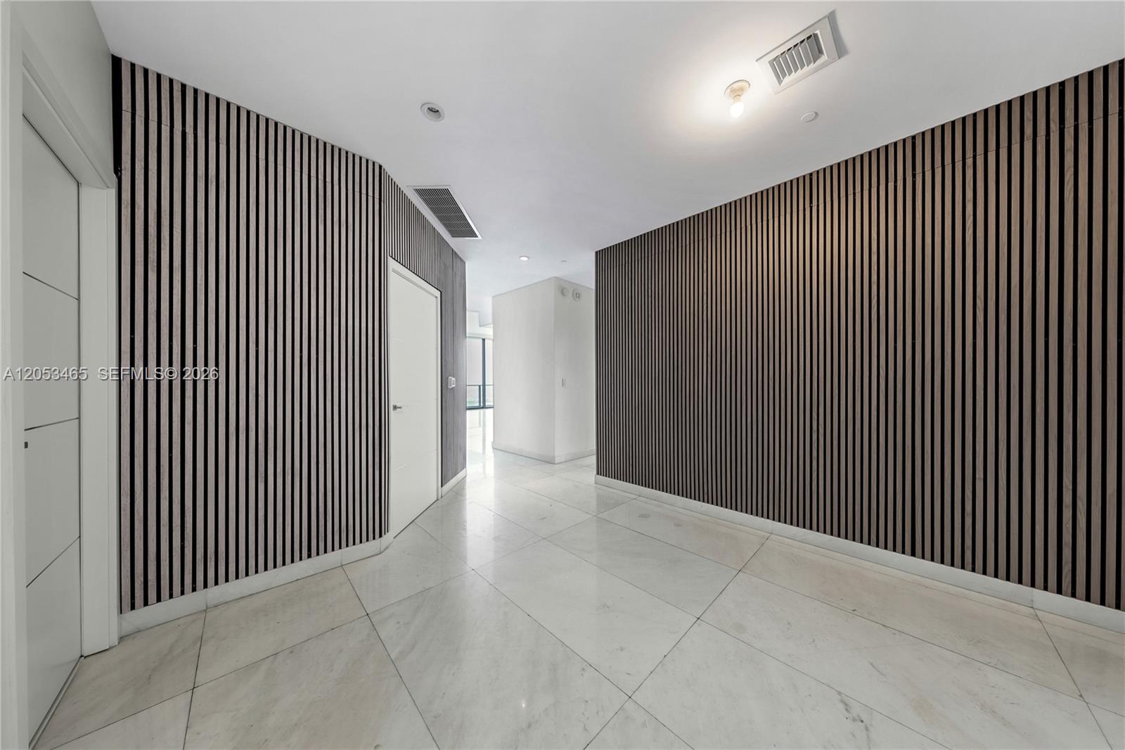 A hallway features white tile flooring and walls accented with vertical wood slat paneling — 1300 S Miami Ave, Miami FL 33130, MIAMI, FL