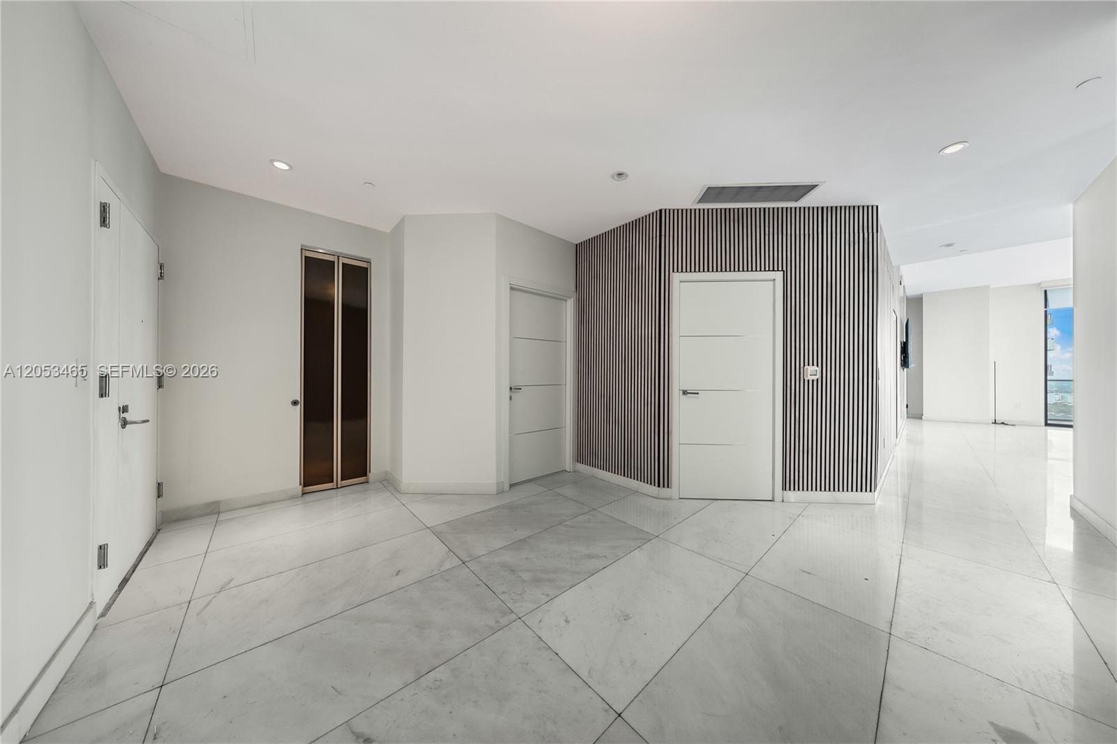 A bright foyer with white marble floors, paneled walls, and multiple white doors — 1300 S Miami Ave, Miami FL 33130, MIAMI, FL