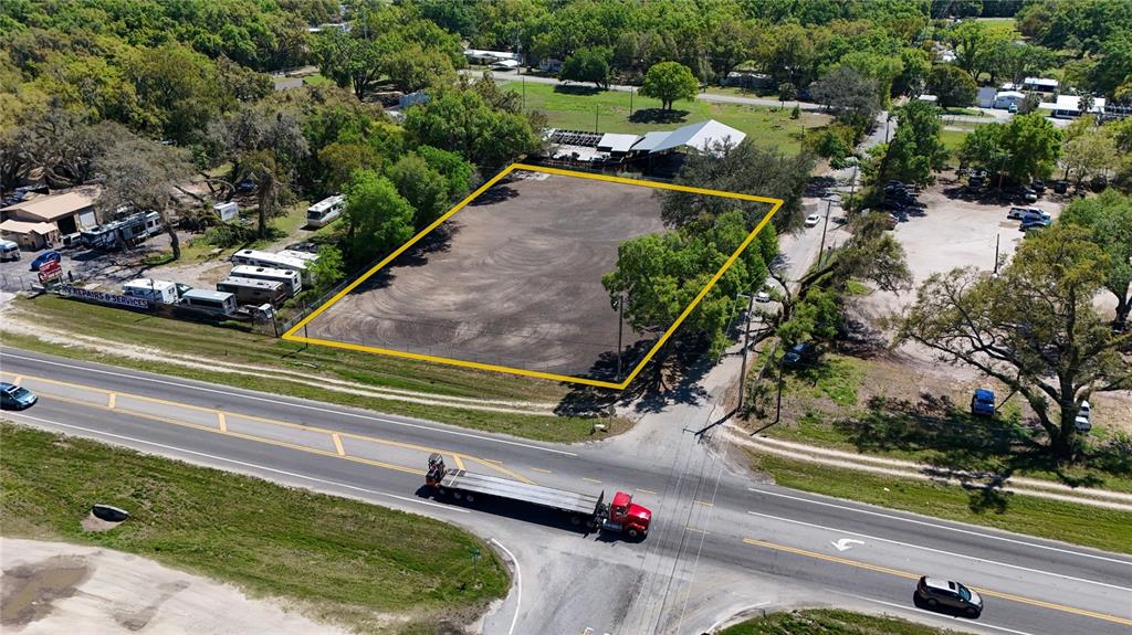 An aerial view shows a vacant, rectangular dirt lot outlined in yellow near a road — 11703 N US 301 HIGHWAY, THONOTOSASSA, FL