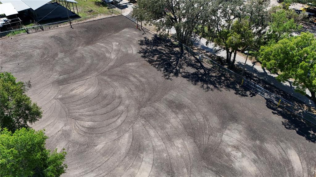 An aerial view of a vacant, fenced dirt lot with tire tracks and surrounding trees — 11703 N US 301 HIGHWAY, THONOTOSASSA, FL