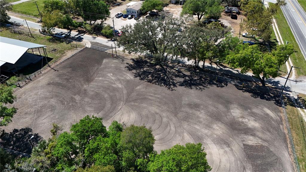 An aerial view shows a cleared, fenced dirt lot with tire tracks and surrounding trees — 11703 N US 301 HIGHWAY, THONOTOSASSA, FL