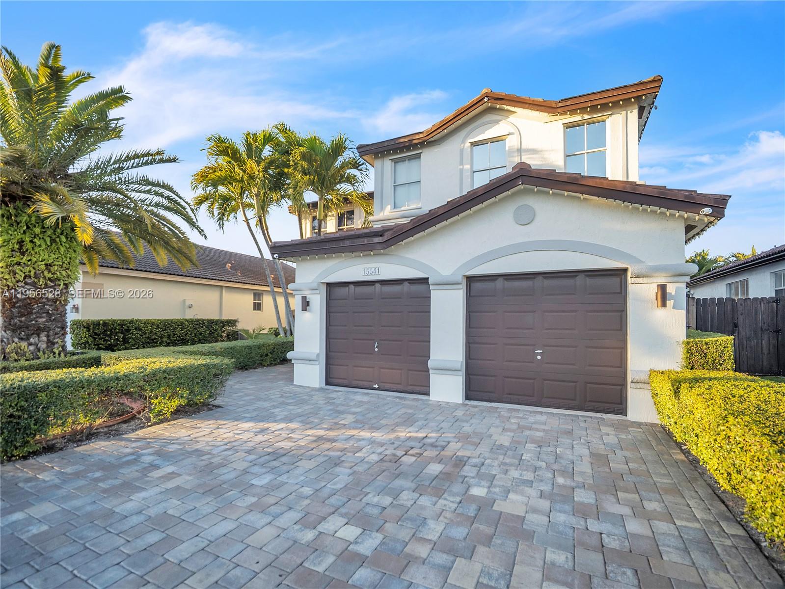 A two-story house features a two-car garage, a paved driveway, and palm trees — 15541 SW 21st Ter, Miami FL 33185, MIAMI, FL