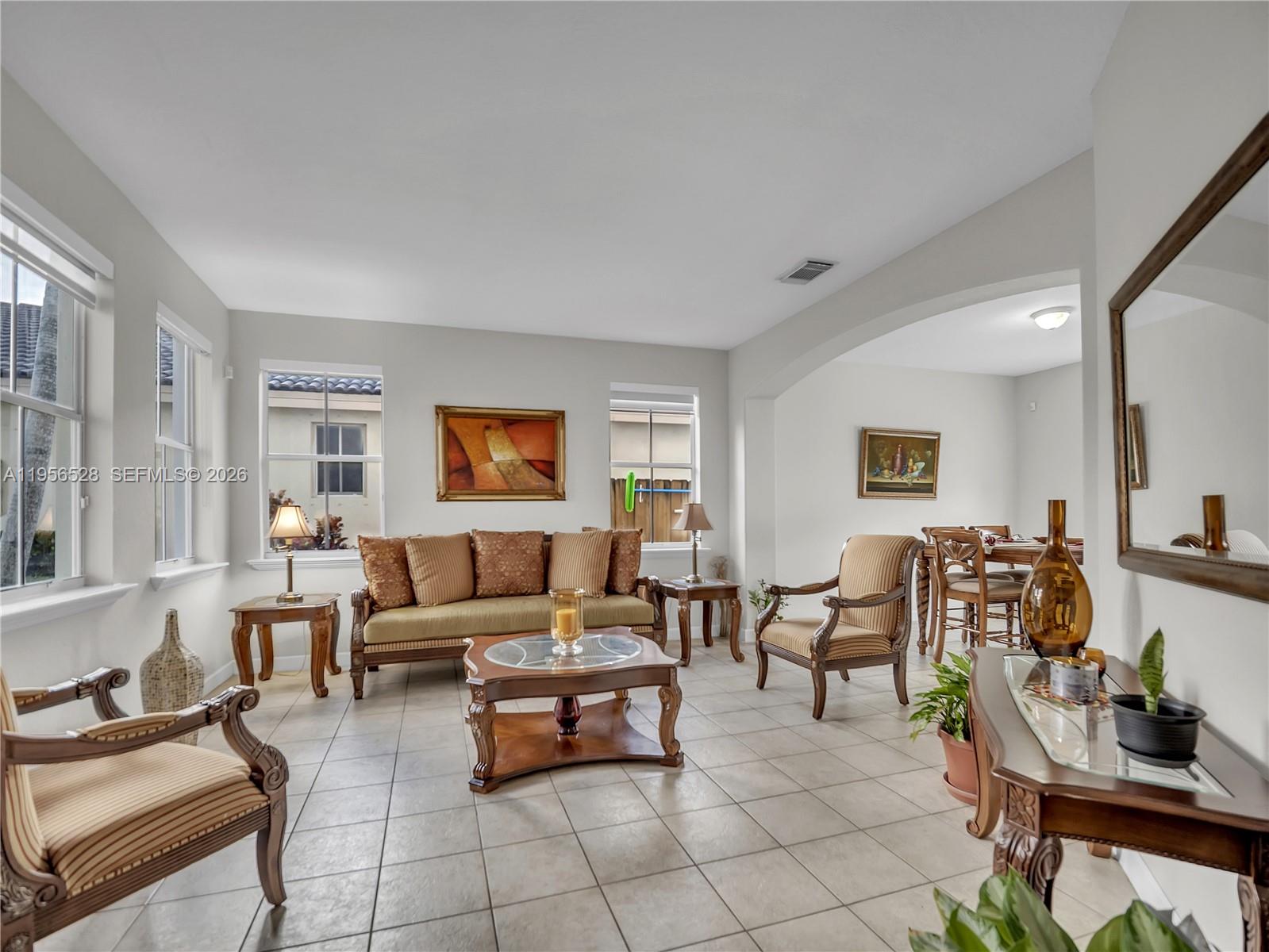 A living room with tile flooring, a sofa, two armchairs, and a dining area beyond — 15541 SW 21st Ter, Miami FL 33185, MIAMI, FL