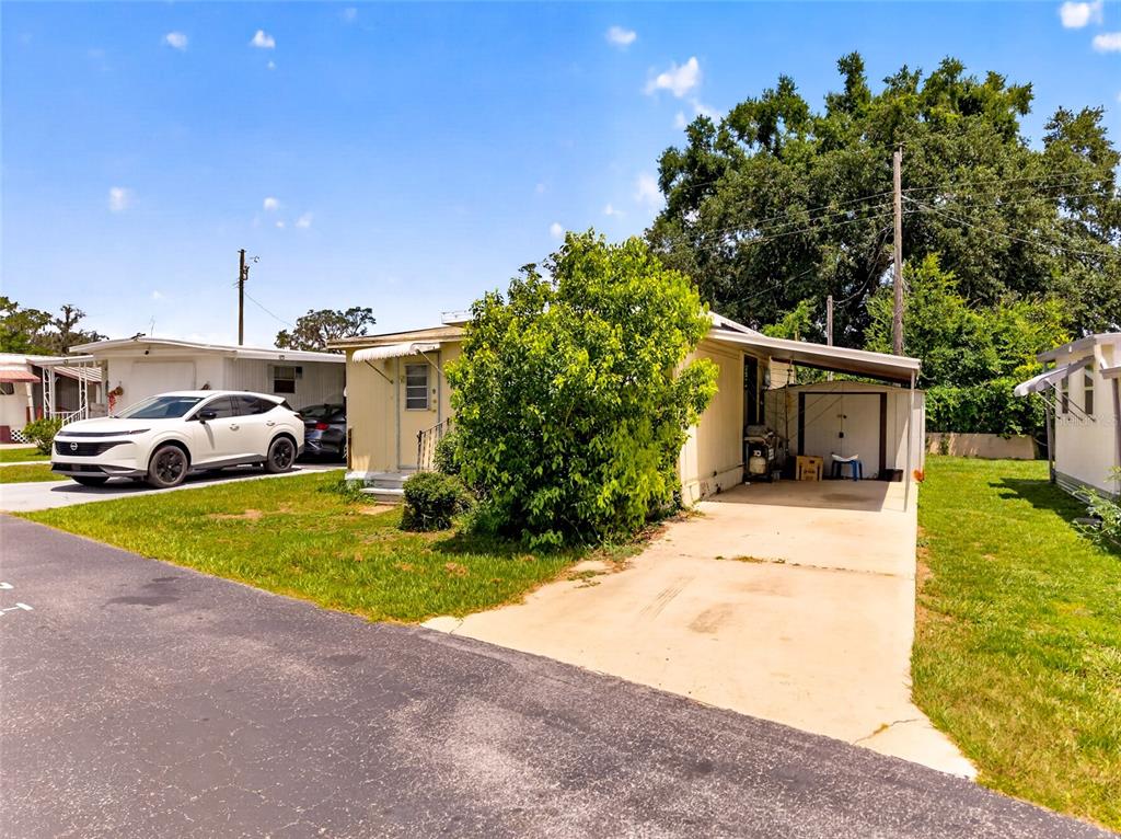 A single-story house with a carport, a white SUV, and a large bush in front — 37433 RAY DRIVE, ZEPHYRHILLS, FL