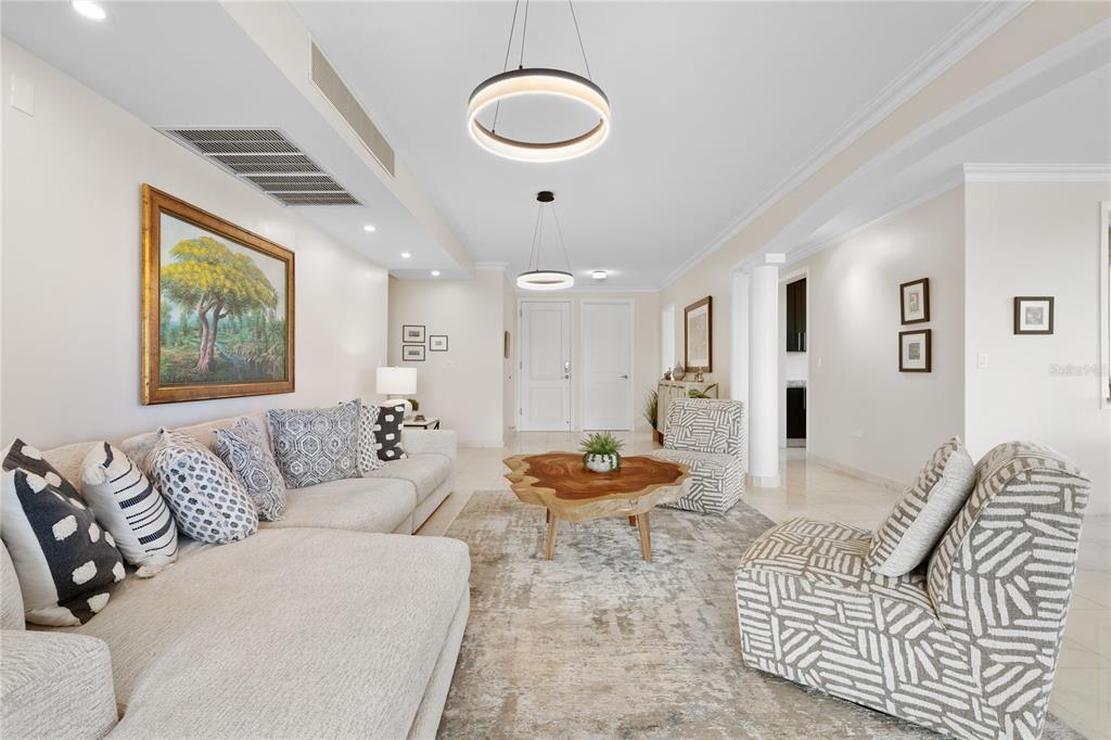 A living room features a sectional sofa, two patterned armchairs, and a live-edge coffee table — 406 COCO BEACH BVL UNIT 401A, RIO GRANDE, PR