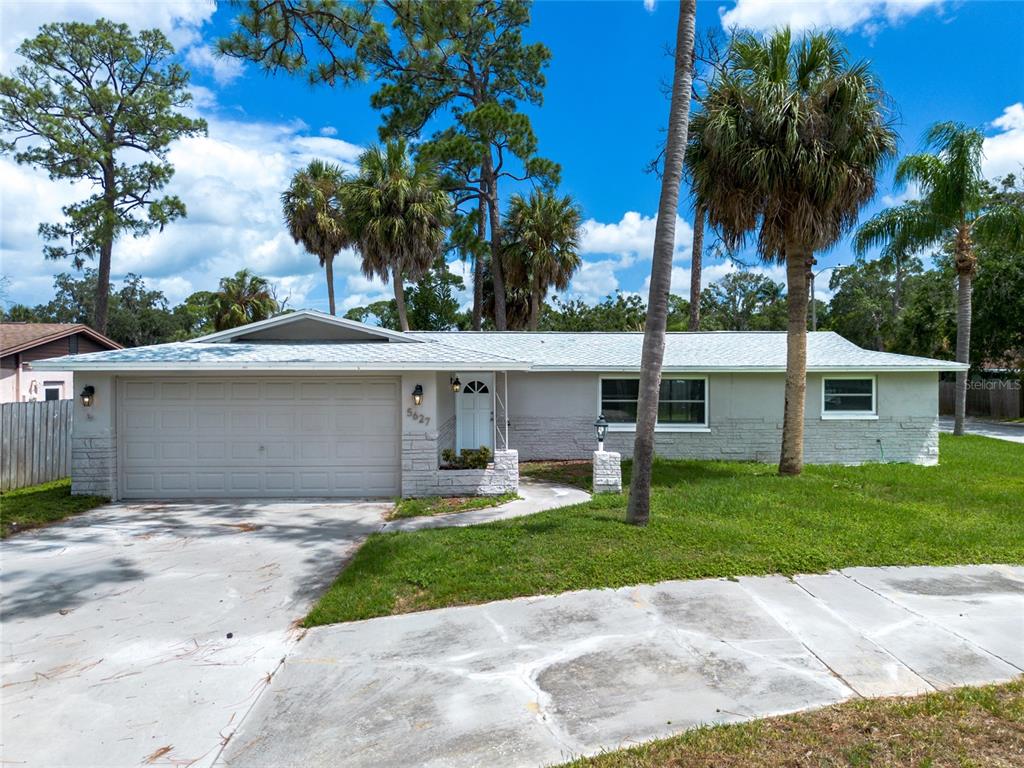 A single-story house with a light gray exterior, a two-car garage, and palm trees — 5627 BERLIN DRIVE, PORT RICHEY, FL
