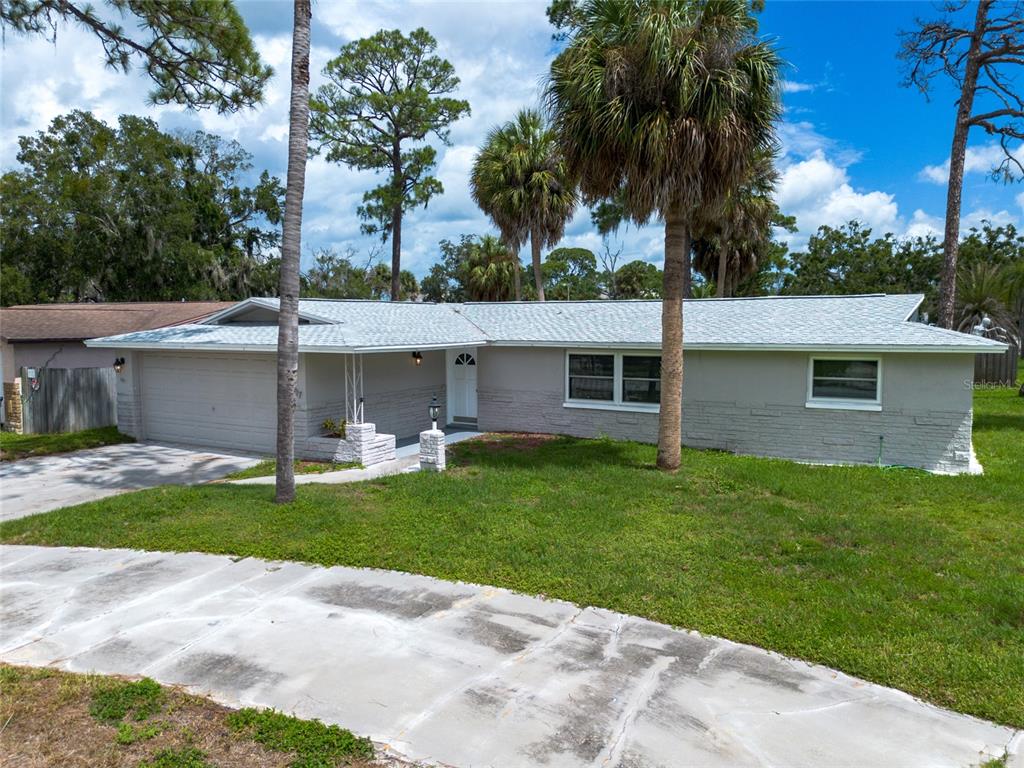 A single-story house with a gray exterior, a two-car garage, and palm trees in front — 5627 BERLIN DRIVE, PORT RICHEY, FL
