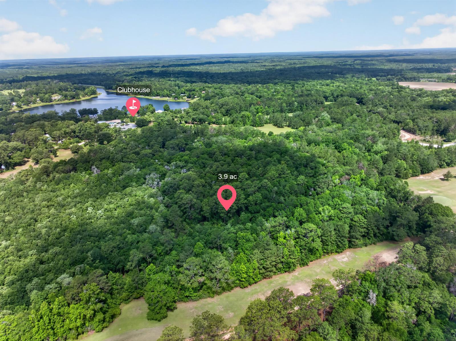 This aerial view shows a wooded 3.9-acre lot near a clubhouse and a lake — 2744-2748 Little John Lane, FL 32425, FL