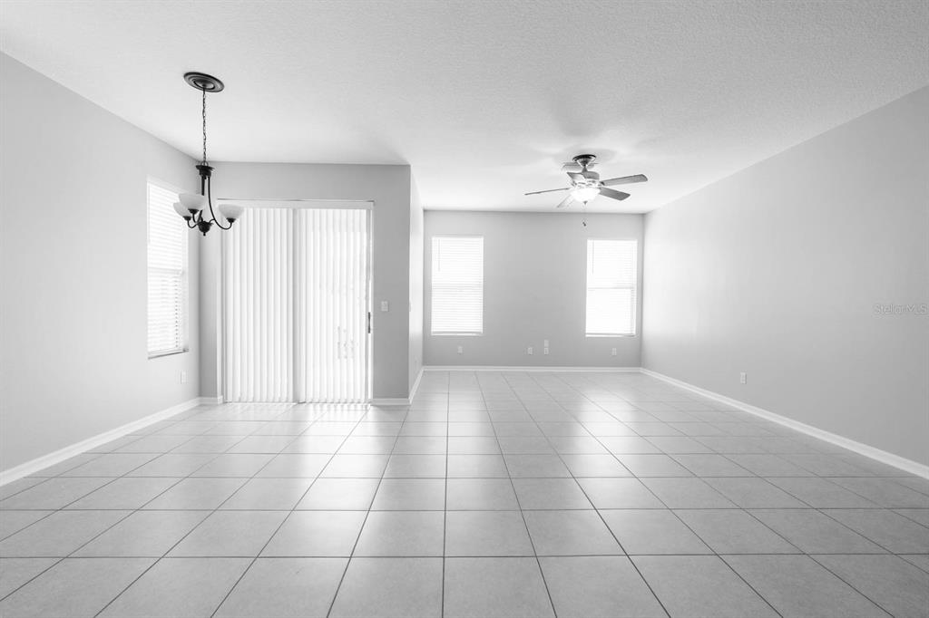 A bright, open-concept living and dining area features light-colored tile flooring and a ceiling fan — 9326 WATCHET WAY, ORLANDO, FL