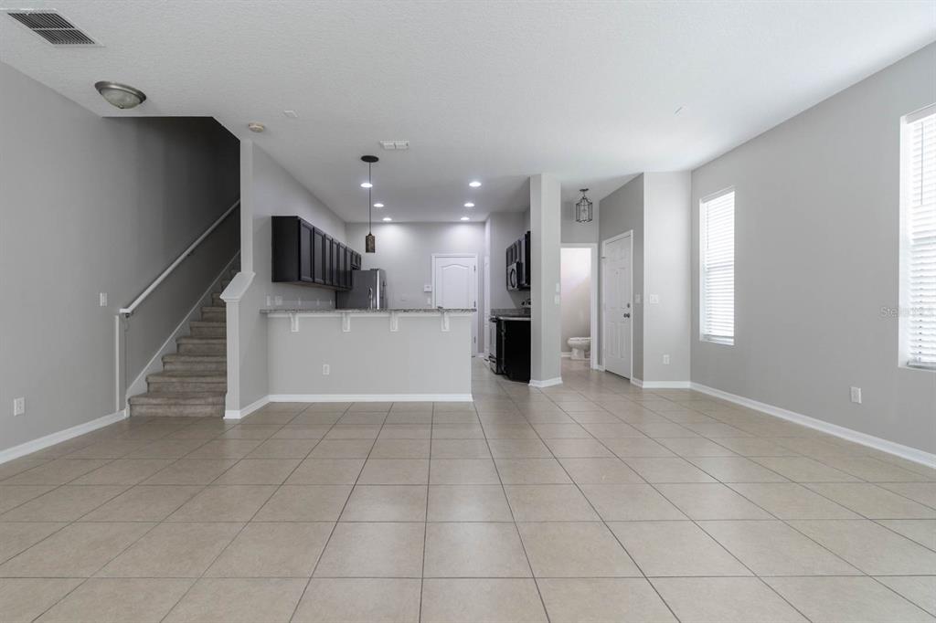 An open-concept living area features tile flooring, a staircase, and a kitchen with dark cabinets — 9326 WATCHET WAY, ORLANDO, FL