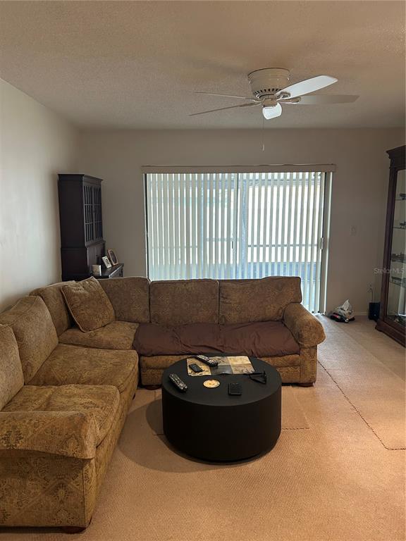 A living room features a tan sectional sofa, a round coffee table, and a ceiling fan — 807 BUCKIE DRIVE, WINTER SPRINGS, FL