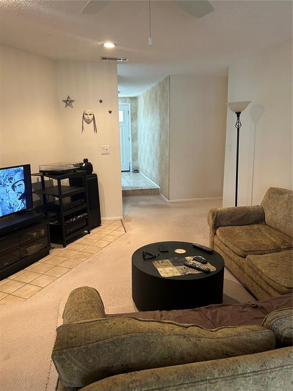 A living room features a television, a round coffee table, and a patterned sofa — 807 BUCKIE DRIVE, WINTER SPRINGS, FL