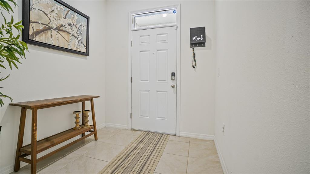A tiled entryway features a wooden console table, a wall-mounted mail holder, and a white door — 365 FELTRIM RESERVE BOULEVARD, DAVENPORT, FL