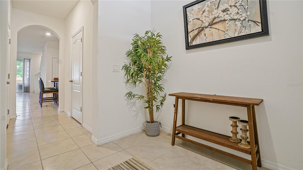 A tiled entryway features a wooden console table, a potted plant, and wall art — 365 FELTRIM RESERVE BOULEVARD, DAVENPORT, FL