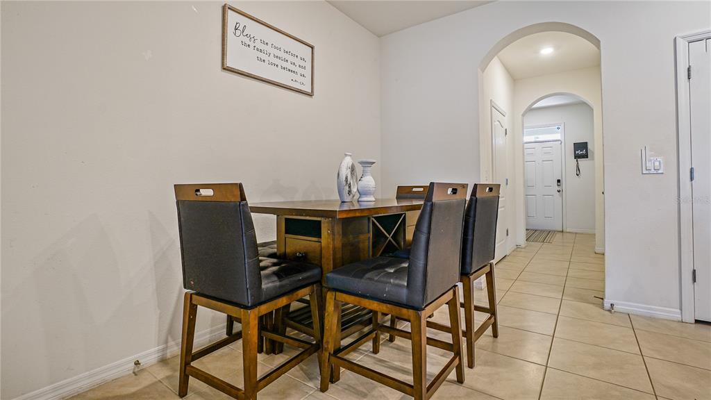 A dining area features a wooden table with four chairs and a wall-mounted sign — 365 FELTRIM RESERVE BOULEVARD, DAVENPORT, FL