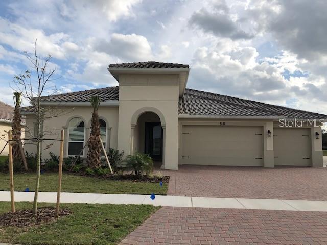 A single-story house with a tiled roof, beige stucco exterior, and a three-car garage — 3181 AGOSTINO TERRACE, KISSIMMEE, FL
