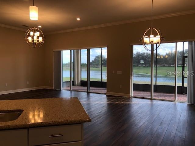 A kitchen island overlooks a living area with large sliding glass doors facing a lake — 3181 AGOSTINO TERRACE, KISSIMMEE, FL