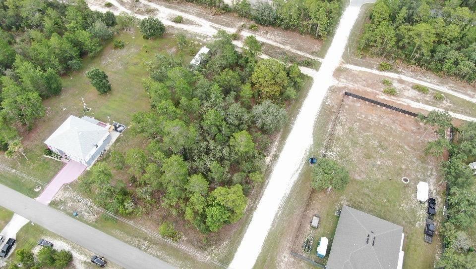 An aerial view shows a wooded vacant lot situated between two residential properties and roads — 11200 MARVELWOOD ROAD, WEEKI WACHEE, FL