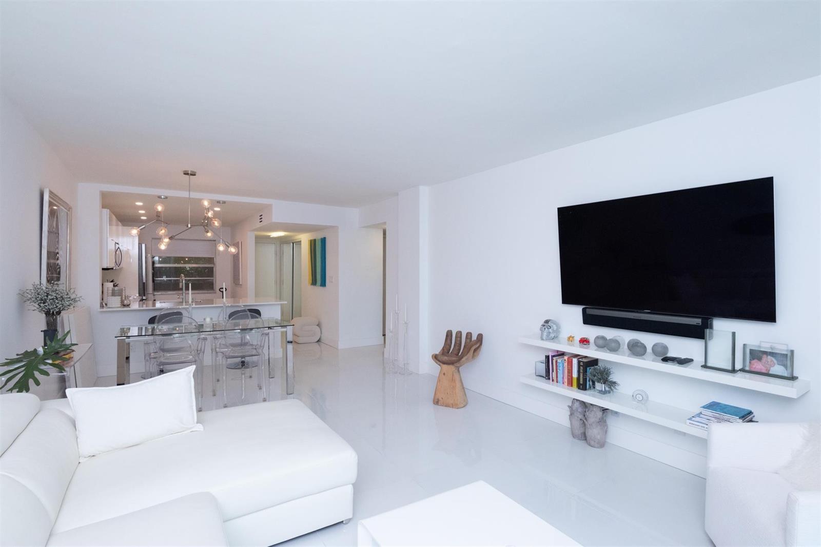 A bright living room features white flooring, a wall-mounted television, and an adjacent dining area — 3581 S Ocean Boulevard # 2b, Palm Beach FL 33480, PALM BEACH, FL