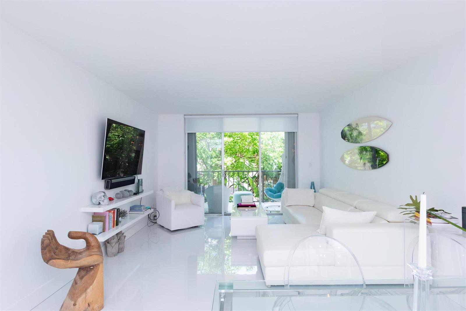 A bright white living room features a sectional sofa, wall-mounted television, and balcony access — 3581 S Ocean Boulevard # 2b, Palm Beach FL 33480, PALM BEACH, FL