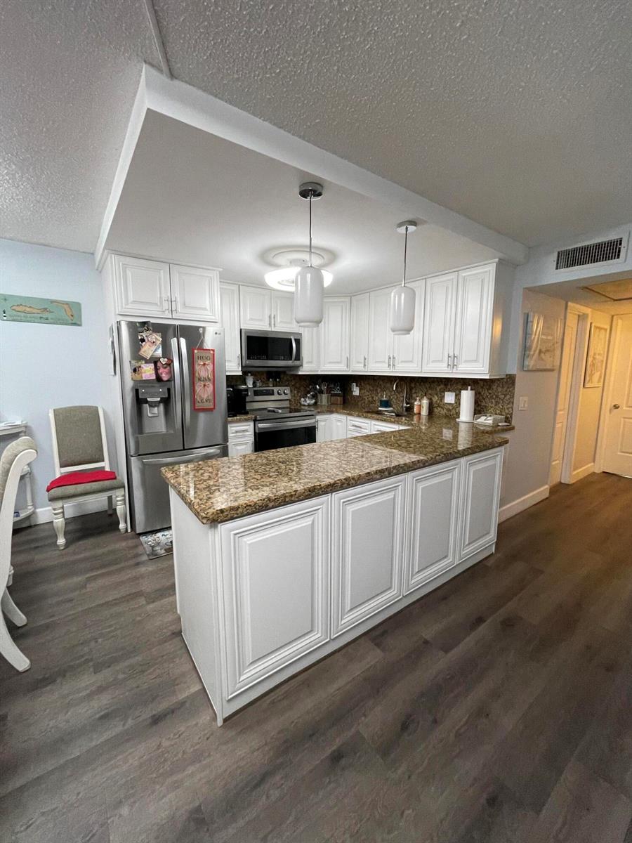 A kitchen features white cabinets, granite countertops, stainless steel appliances, and wood-look flooring — 3021 Ellesmere B # 3021, Deerfield Beach FL 33442, DEERFIELD BEACH, FL
