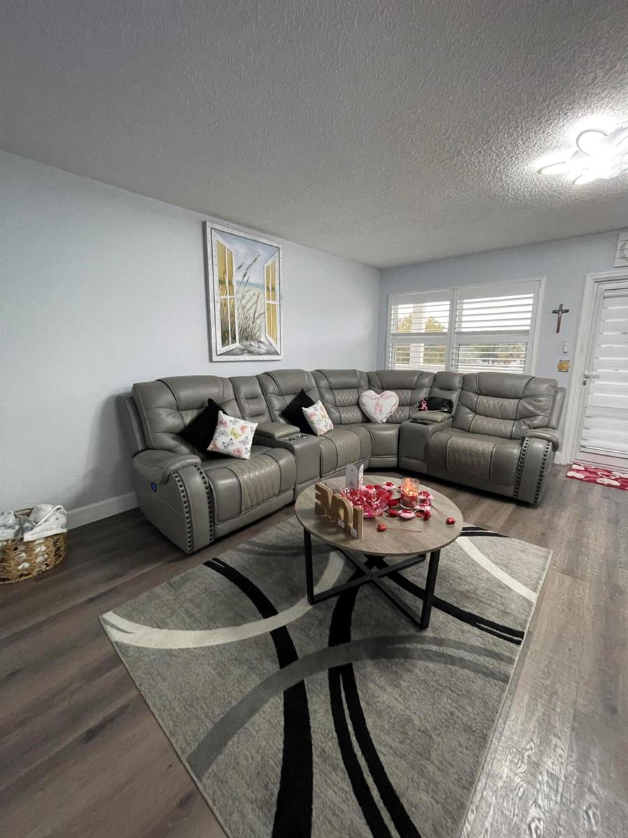 A living room features a gray sectional sofa, a round coffee table, and a patterned rug — 3021 Ellesmere B # 3021, Deerfield Beach FL 33442, DEERFIELD BEACH, FL