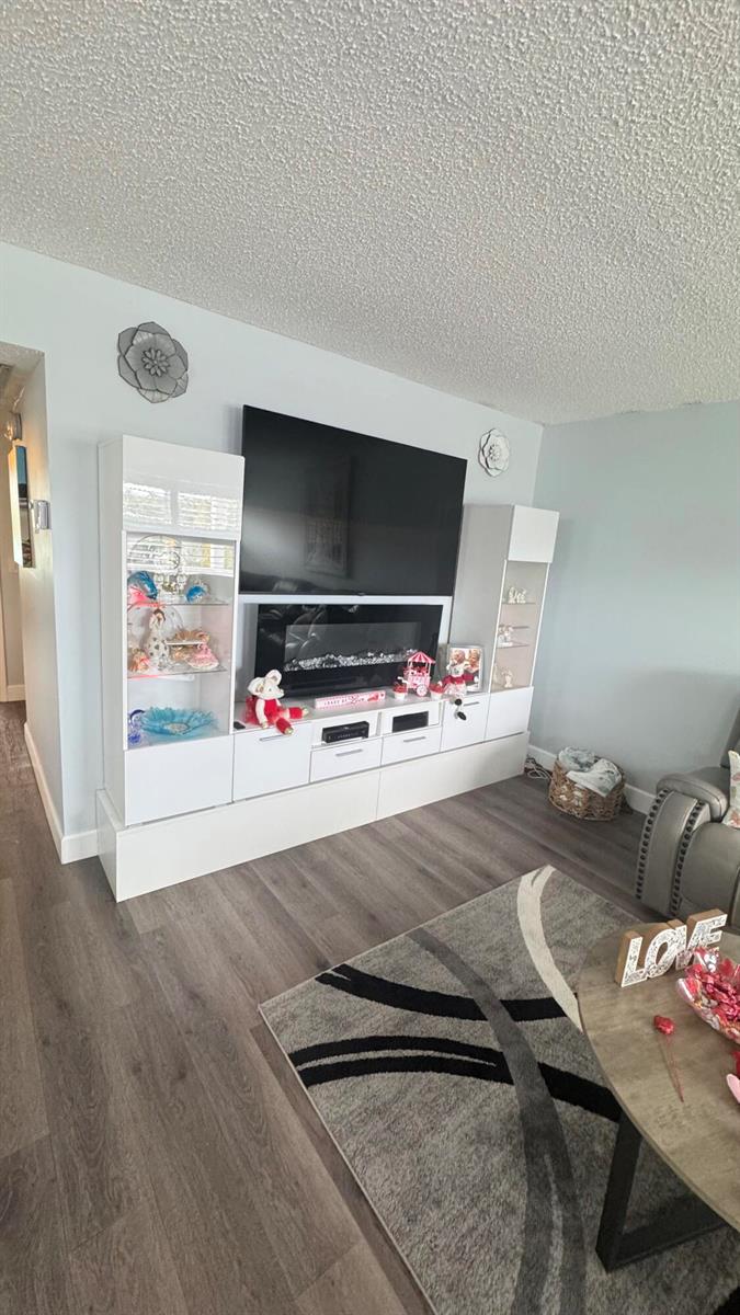 A living room features a white entertainment center with a fireplace, television, and display cabinets — 3021 Ellesmere B # 3021, Deerfield Beach FL 33442, DEERFIELD BEACH, FL