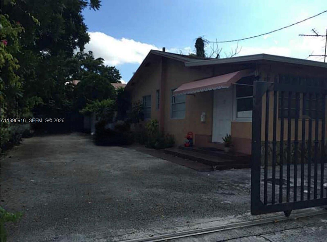 A single-story house with a concrete driveway and a metal gate in the foreground — 2528 SW 16th St, Miami FL 33145, MIAMI, FL