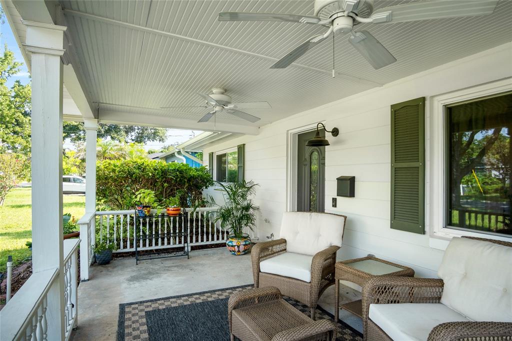 A covered front porch features wicker furniture, ceiling fans, and white siding with green shutters — 501 MERIDALE AVENUE, ORLANDO, FL