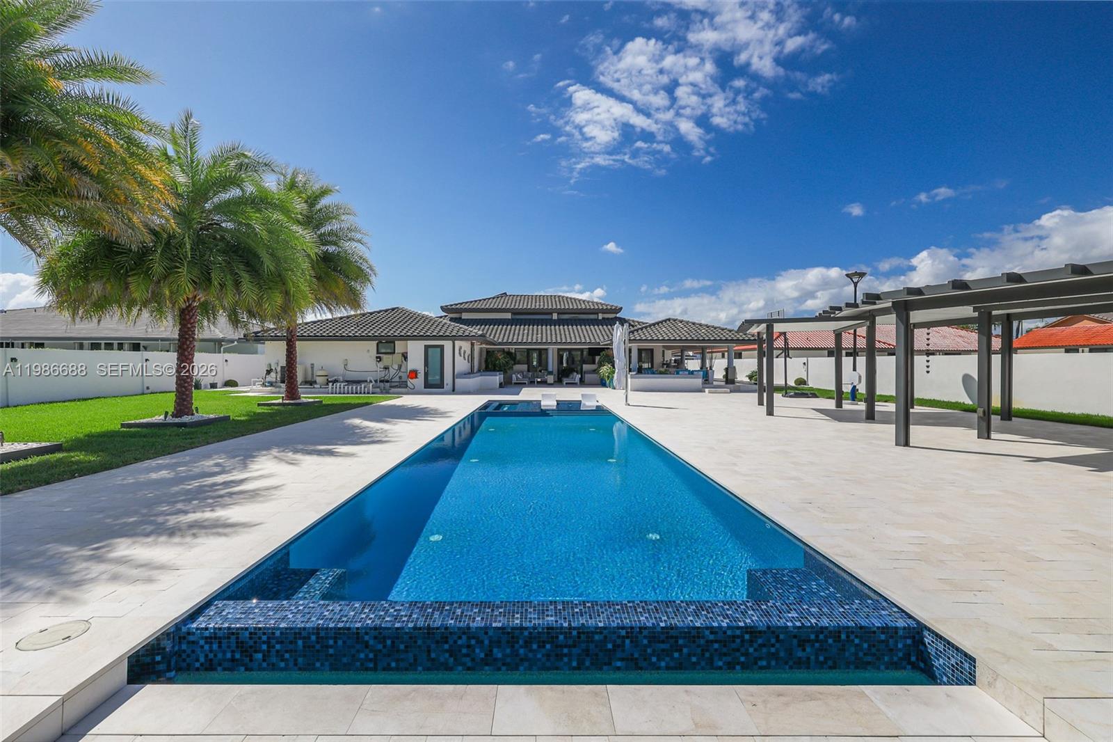 A long rectangular swimming pool sits on a patio in front of a house — 13801 SW 34th St, Miami FL 33175, MIAMI, FL