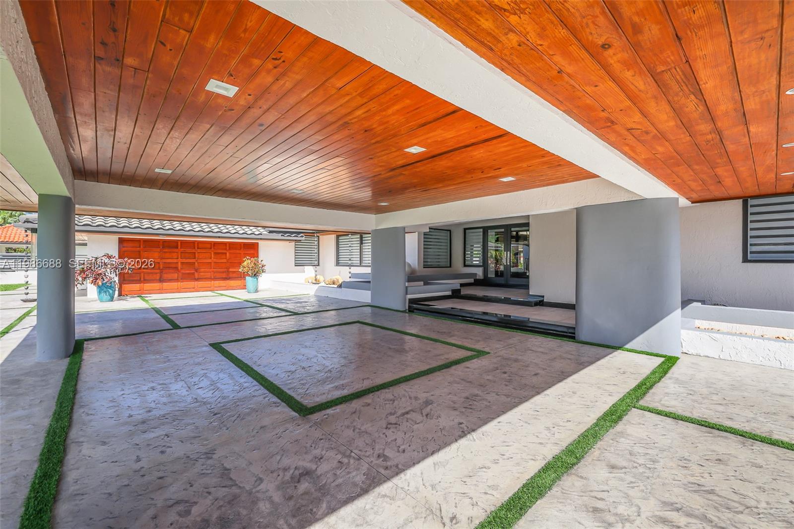 A covered outdoor patio features a wood-paneled ceiling and a stamped concrete floor with grass — 13801 SW 34th St, Miami FL 33175, MIAMI, FL