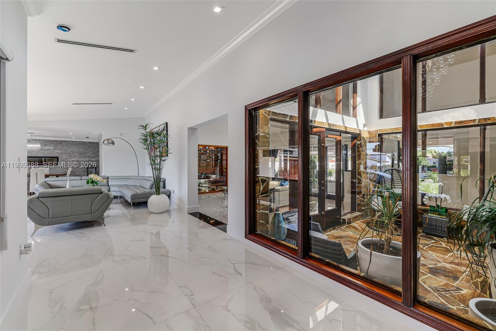 A bright hallway with white marble floors overlooks an interior courtyard through large glass windows — 13801 SW 34th St, Miami FL 33175, MIAMI, FL