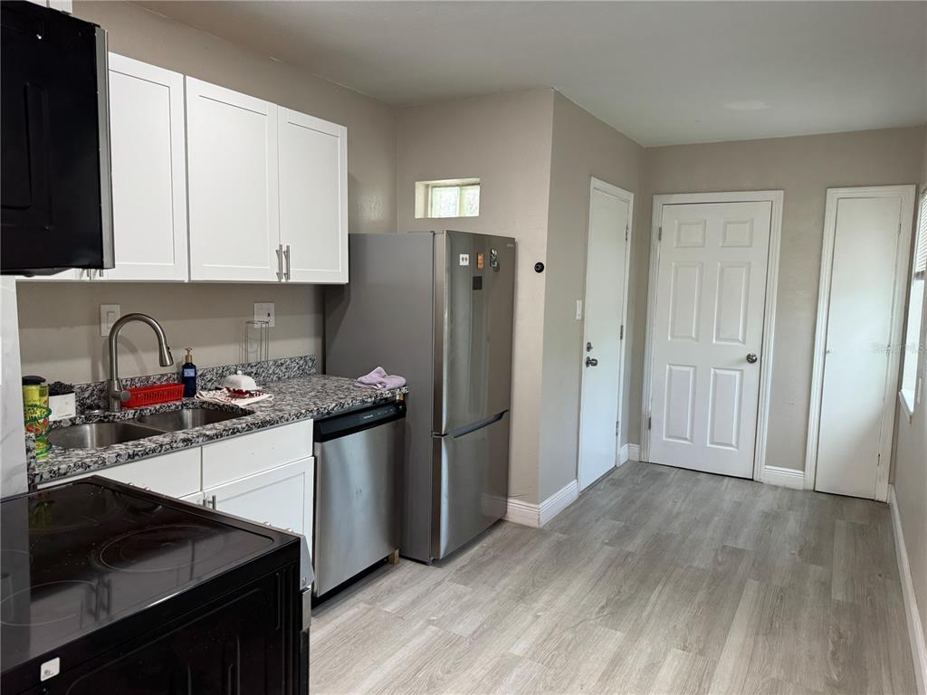 A kitchen features white cabinets, granite countertops, stainless steel appliances, and light wood-look flooring — 3114 58TH AVENUE N, ST PETERSBURG, FL